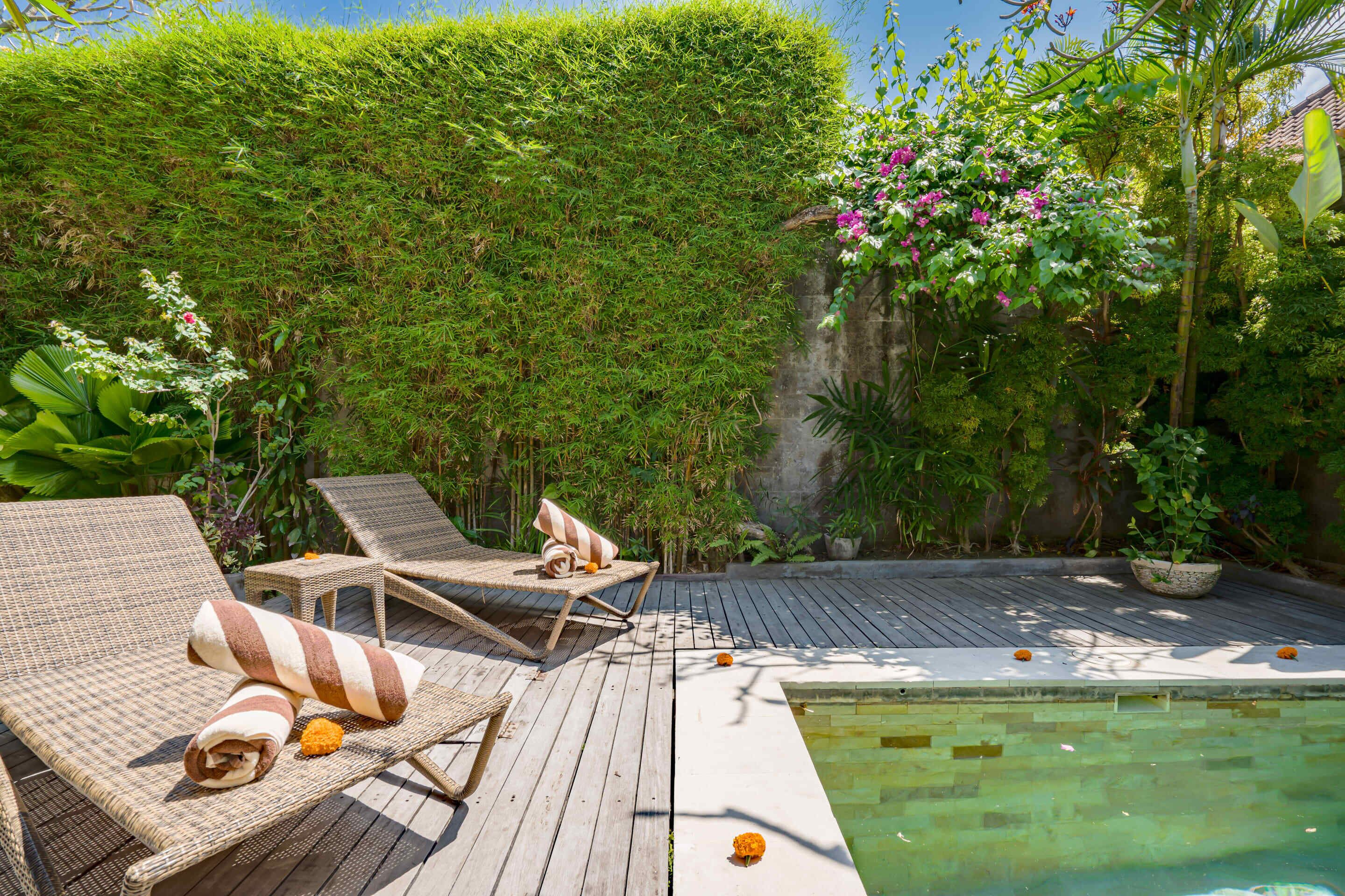 A wooden deck with lounge chairs and a pool.
