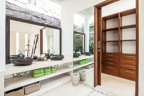 A bathroom with a large mirror, two sinks, and a wooden vanity with drawers.