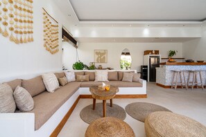 A modern living room with a sectional sofa, a wooden coffee table, and woven poufs. - Villa Kambodja (Seminyak)