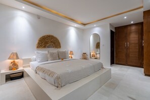 Une chambre moderne avec un grand lit, des lampes de chevet, un miroir et une armoire.
