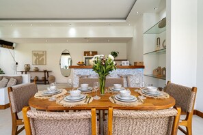 A dining area with a wooden table set for six, surrounded by wicker chairs.