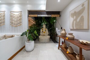 A modern interior with a central statue, potted plants, and decorative items on shelves.