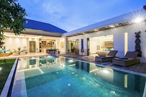 A modern outdoor pool area with lounge chairs and a dining area. - Villa Anak (Seminyak)