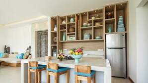 Una cocina moderna con una isla central, taburetes de bar de madera y estantes empotrados con distintos utensilios de cocina.