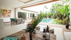 Un amplio salón con vista a la piscina, una mesa de comedor con sillas y un cuadro grande en la pared.