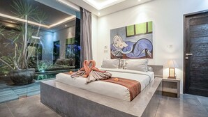 A modern bedroom with a large bed, a glass wall, and a painting on the wall. - Villa Laurent (Seminyak)