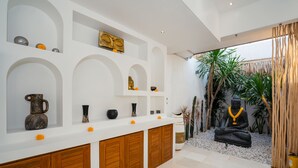 Un intérieur moderne avec un mur blanc, des meubles en bois et une statue représentant une figure assise.