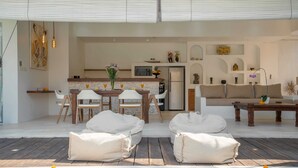 Un espace de vie extérieur moderne, doté d’une piscine, de coins salon et d’une cuisine en arrière-plan.