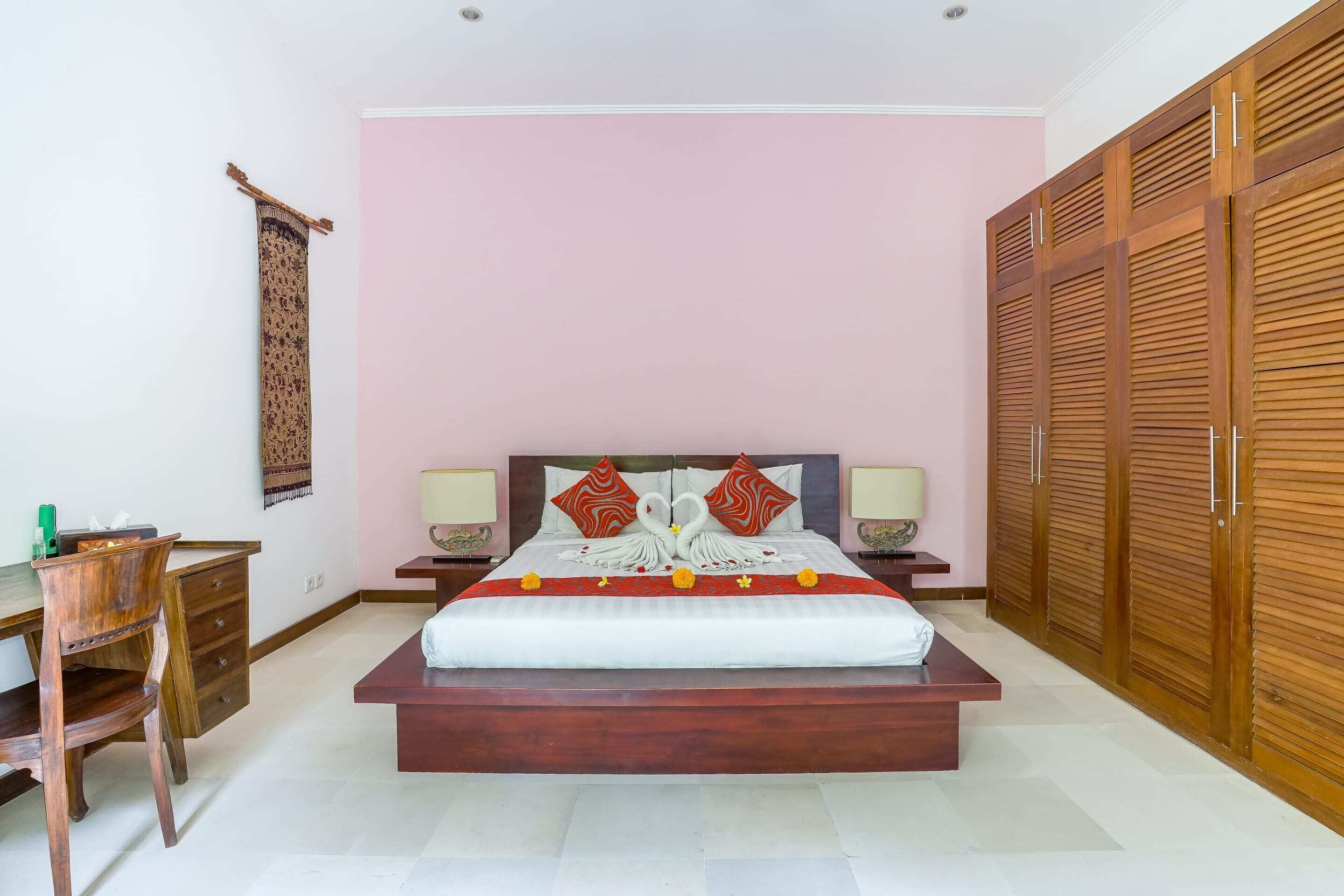 Une chambre à coucher avec un grand lit, une armoire en bois, un bureau et une chaise.