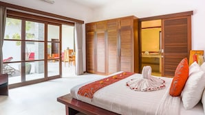 A spacious bedroom with a large bed, sliding wooden doors, and a view of the outdoors. - Villa Suliac (Legian)