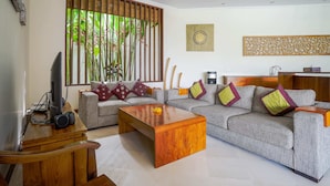 A living room with a sofa, coffee table, and television. - Villa Suliac (Legian)