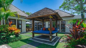 A wooden gazebo with a swing, surrounded by lush tropical plants and a well-maintained lawn. - Villa Athena (Seminyak)