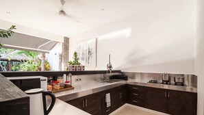 A modern kitchen with dark wood cabinets, stainless steel countertops, and a built-in stove. - Villa Jago (Seminyak)