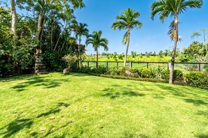 A well-maintained grassy lawn with palm trees and a stone structure.