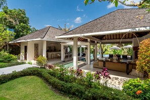 Un espacio al aire libre cubierto con piscina, asientos y comedor.