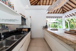 A modern kitchen with a black countertop, stainless steel sink, and a view of the garden through a window.