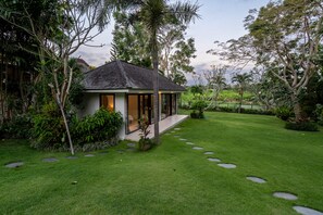 A house with a sloped roof, surrounded by a well-maintained lawn with stepping stones leading to the entrance. - Villa Bali Sari (Canggu)