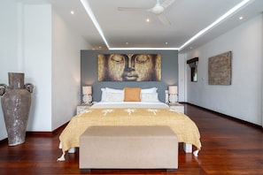 A modern bedroom with a large bed, a ceiling fan, and artwork on the walls.
