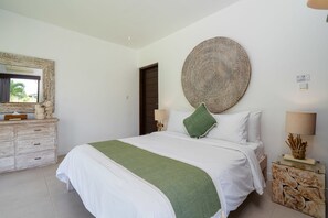 Un dormitorio con una cama grande, un aparador, un espejo, un plato decorativo en la pared y una lámpara de noche.