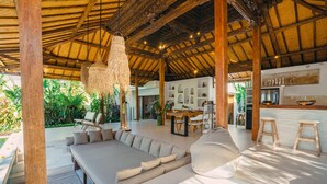 A spacious outdoor lounge with a wooden ceiling, a large sofa, and a dining area. - Villa Marula (Seminyak)