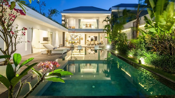 A modern house with a swimming pool, lounge area, and a well-lit interior. - Villa Clemence (Canggu)