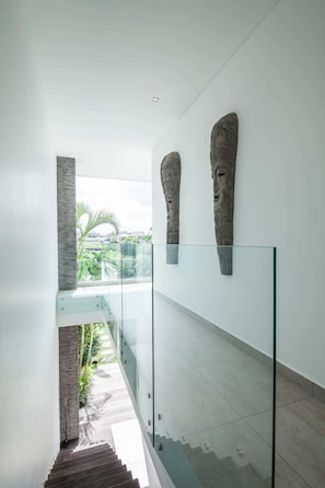 Enjoy the open view from the glass railing, with a staircase leading to a second level and artistic stone sculptures on display.