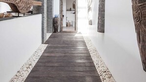 A modern interior with a wooden floor, stone walls, and a skylight. - Villa Elisa (Canggu)