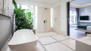 A modern bathroom with a freestanding bathtub, a shower, and a large window providing natural light. - Villa Elisa (Canggu)