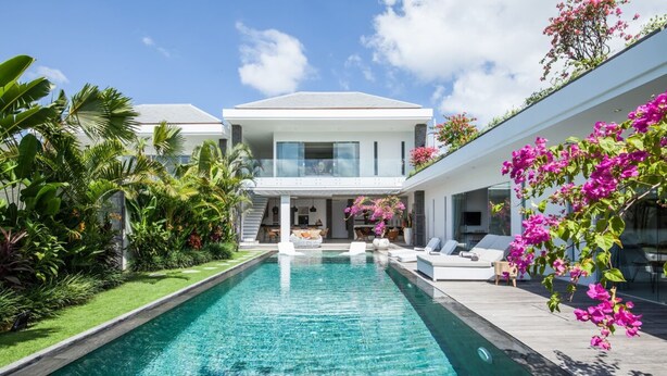 A modern house with a swimming pool, surrounded by lush greenery and pink flowers. - Villa Elisa (Canggu)