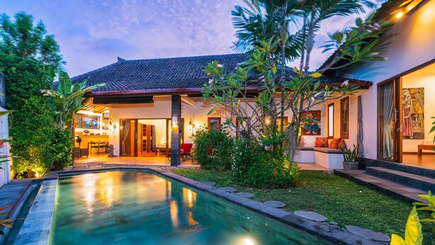 Une maison moderne dotée d’une piscine, d’un patio couvert et d’une végétation luxuriante.