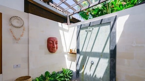 Un espace de détente avec un mur en pierre, une douche et un masque décoratif accroché au mur.
