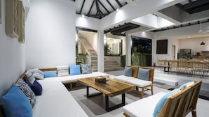 A spacious living area with a large sofa, a wooden coffee table, and a dining area with chairs and a table. - Villa Ananda (Canggu)