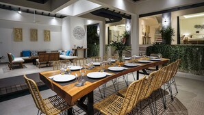 A dining area with a long wooden table set for six, surrounded by wicker chairs. - Villa Ananda (Canggu)