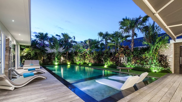 Un área de piscina con sillones de descanso y una terraza de madera.