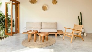 Un salon moderne avec un canapé, une table d’appoint en bois et un fauteuil en rotin.