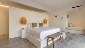 Une chambre moderne avec un grand lit, des tables de chevet, un banc et des œuvres d’art décoratives au mur.