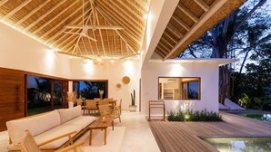 A modern outdoor living area with a wooden deck, a pool, and a dining set. - Villa Lumahi Tiga (Cemagi)