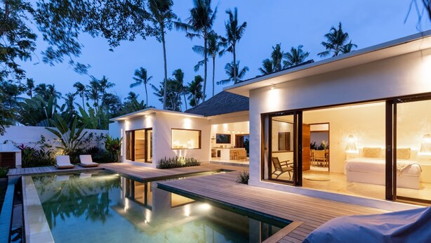 A modern resort with a swimming pool, wooden deck, and a well-lit interior. - Villa Lumahi Tiga (Cemagi)