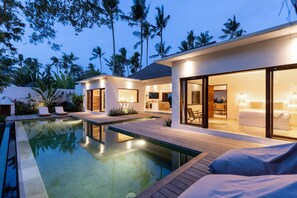 A modern resort with a swimming pool, wooden deck, and a well-lit interior. - Villa Lumahi Tiga (Cemagi)