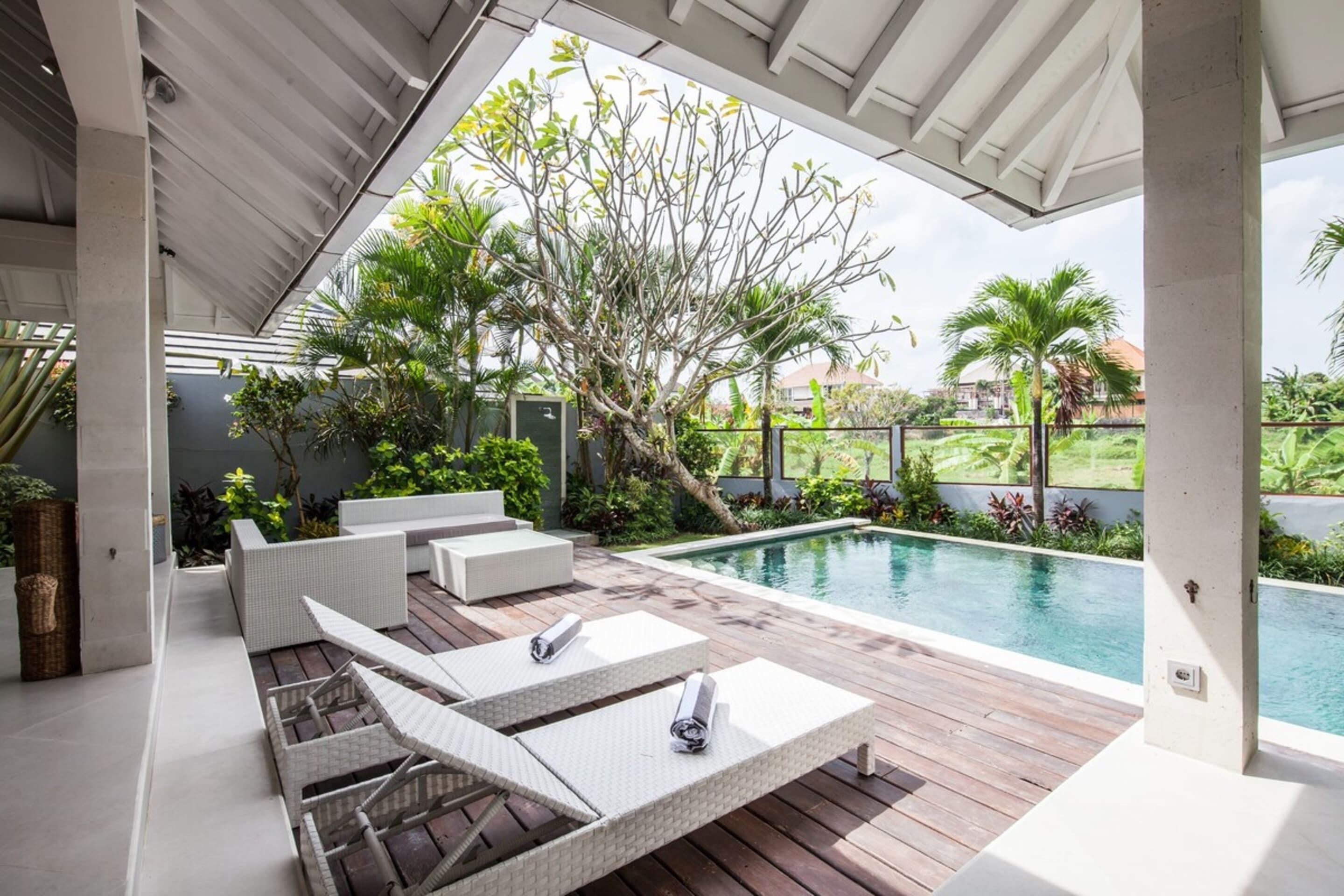 A modern outdoor pool area with lounge chairs and a wooden deck.