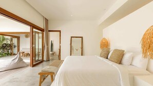 A modern bedroom with a large bed, a bench, and a view of the outdoors. - Villa Lumahi Dua (Cemagi)