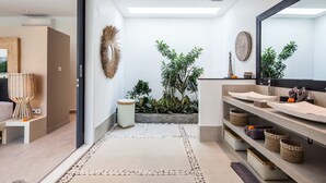 A modern bathroom with a large mirror, two sinks, and a built-in shelf with baskets. - Villa Hugo (Canggu)