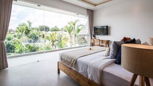 A modern bedroom with a large bed, a round table, and a TV. - Villa Hugo (Canggu)
