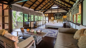 Une pièce spacieuse avec un plafond haut et des poutres en bois, un lit, un canapé et une table agrémentée d’objets décoratifs.