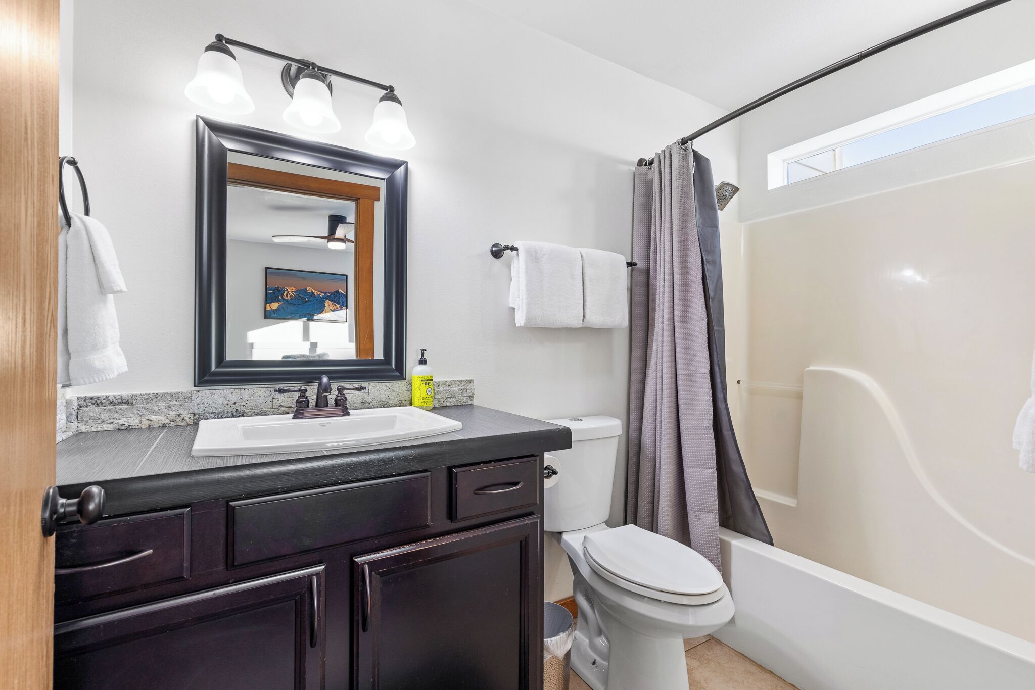 Un baño con lavamanos, espejo, inodoro y cortina de ducha.
