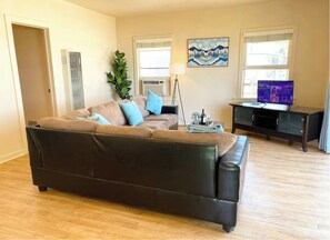 Relax in this stylish living room with a large sofa, flat-screen TV, and potted plant.