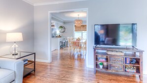 Un soggiorno moderno con televisione, mobile TV in legno e zona pranzo con sedie e tavolo.