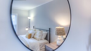 Una camera da letto con un letto, una lampada da comodino e uno specchio che riflette l'ambiente.