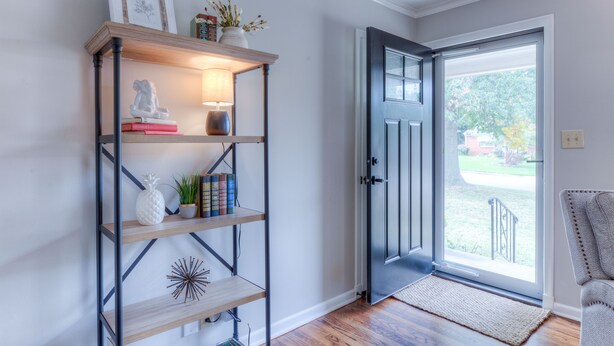 Un corridoio con una libreria in legno, una porta nera e vista sull'esterno.