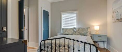 A bedroom with a bed, a nightstand, a lamp, a window with blinds, and a ceiling fan.